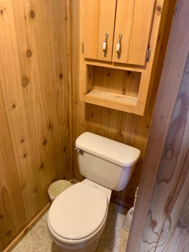 a bathroom with a white toilet and wooden walls at Bearlodge Mountain Resort in Sundance