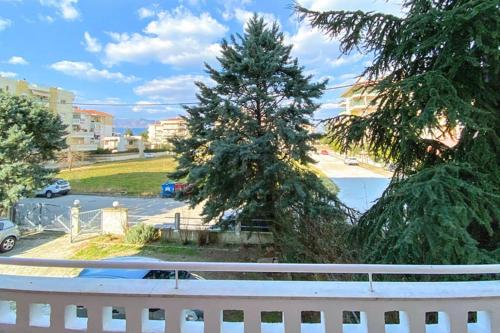 a white fence and a pine tree on a street at Art decor luxury apartment in Komotini