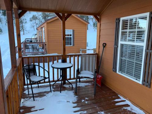 a porch with a table and chairs in the snow at Bearlodge Mountain Resort in Sundance