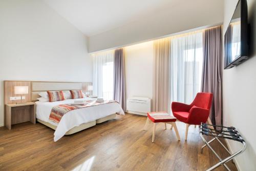 a hotel room with a bed and a red chair at Casas Amarelas Azores in Ponta Delgada