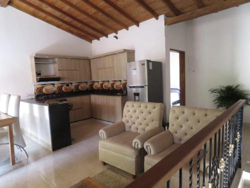 a living room with a couch and a kitchen with a refrigerator at Villa del Socorro in Jardin