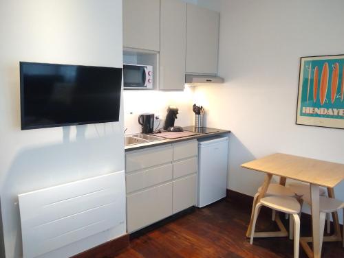 a small kitchen with a small table and a television at Appartement rénové 2 chambres centre historique in Bordeaux