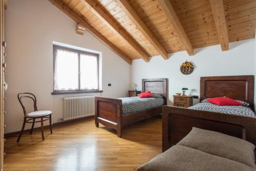 una camera da letto con due letti, una sedia e una finestra di Casa La Guarda a Stenico