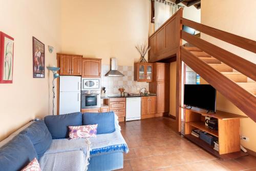 sala de estar con sofá azul y cocina en Casa Rural La Pestilla 1, en El Pinar de El Hierro