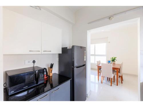 a kitchen with a stainless steel refrigerator and a table at Olive Service Apartments Hitech City in Hyderabad