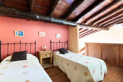 El Pinar del HierroにあるCasa Rural La Pestilla 1の赤い壁と木製の天井が特徴の客室で、ベッド2台が備わります。