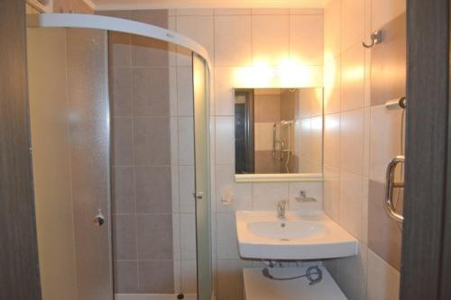 a bathroom with a sink and a shower with a mirror at Sparta Apartments Kosmonaudi in Narva