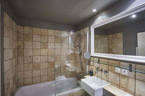 een badkamer met een bad, een wastafel en een spiegel bij Gîte Le Logis - Manoir le Plessix Madeuc in Corseul