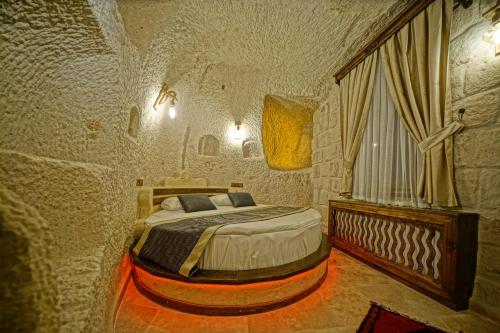 ein Schlafzimmer mit einem Bett in einem Steinzimmer in der Unterkunft Castle Cave Hotel in Goreme