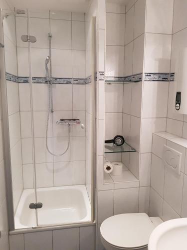 a white bathroom with a shower and a toilet at Sandburg in Schillig