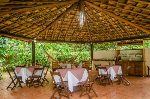 una sala da pranzo con tavoli e sedie sotto un tetto in legno di Espaço Pégasus a Trancoso