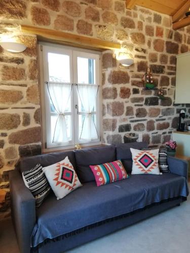 a blue couch in a room with a stone wall at Lithos Residence Poros in Poros