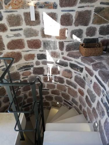 a stone wall with two chairs and a table at Lithos Residence Poros in Poros