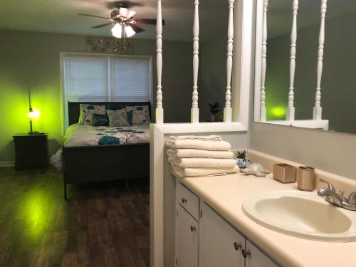 een badkamer met een wastafel en een bed met een spiegel bij True-Mates Stay 5 minutes from Fort Bragg in Fayetteville