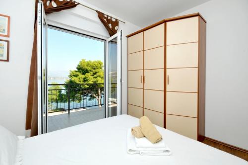 ein Schlafzimmer mit einem Bett und einem großen Fenster in der Unterkunft Apartments Penić in Trogir