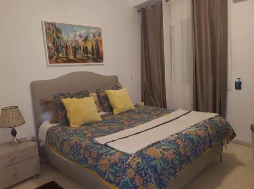 a bedroom with a bed with yellow pillows and a painting at Agreable Appartement Ennasr 2 in Ariana