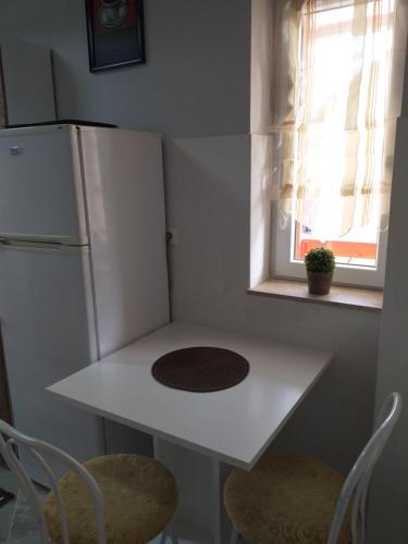 a small kitchen with a white table and a refrigerator at Fiesta Apartman in Miskolctapolca