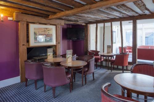 a restaurant with wooden tables and chairs and purple walls at Holiday Inn Ashford Central by IHG in Ashford