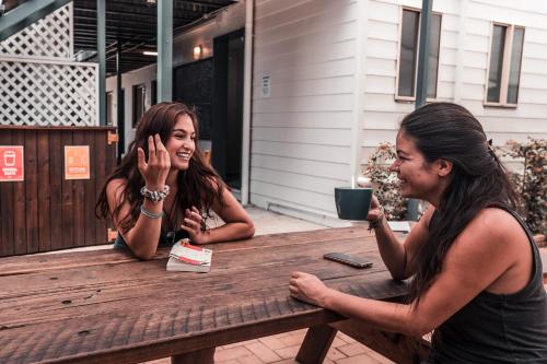 two women sitting at a wooden picnic table at Budds In Surfers Backpackers in Gold Coast
