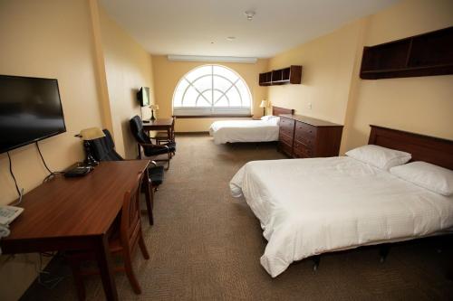 Habitación de hotel con 2 camas, escritorio y TV. en StFX University Summer Hotel, en Antigonish