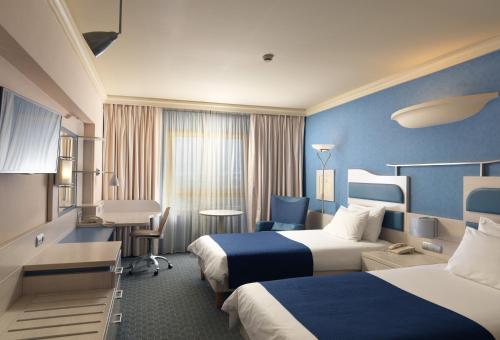 Holiday Inn Athens Attica Av, Airport W., an IHG Hotel في أثينا: غرفة فندقية بسريرين ومكتب