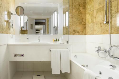 a white bathroom with a tub and a sink at Holiday Inn Athens Attica Av, Airport W., an IHG Hotel in Athens