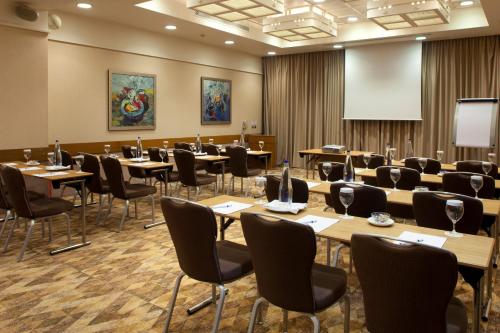 a conference room with tables and chairs and a screen at Holiday Inn Athens Attica Av, Airport W. by IHG in Athens