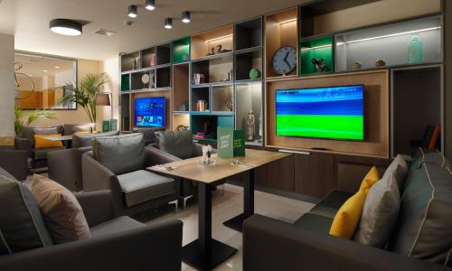 a restaurant with a table and chairs and a tv at Holiday Inn Athens Attica Av, Airport W. by IHG in Athens