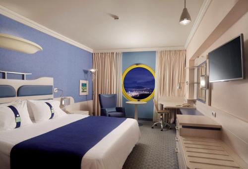a hotel room with a large bed and a desk at Holiday Inn Athens Attica Av, Airport W. by IHG in Athens