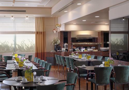 a restaurant with tables and chairs and a bar at Holiday Inn Athens Attica Av, Airport W. by IHG in Athens