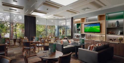 a restaurant with tables and chairs and a flat screen tv at Holiday Inn Athens Attica Av, Airport W. by IHG in Athens
