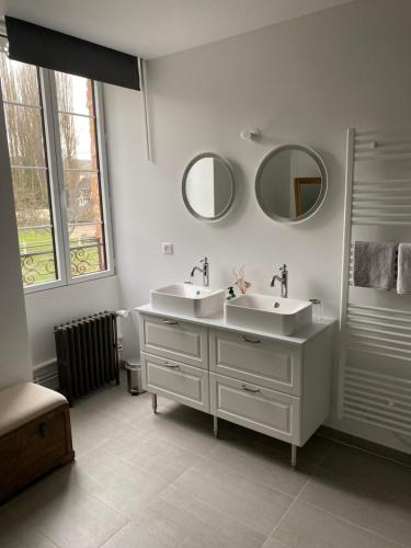 a bathroom with two sinks and two mirrors at Le Moulin Bleu in Saint Cyr-sous-Dourdan