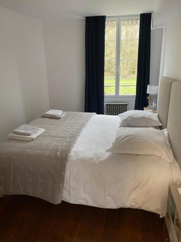 a bedroom with a large white bed with a window at Le Moulin Bleu in Saint Cyr-sous-Dourdan