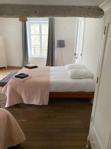 a bedroom with a large bed with a window at Le Moulin Bleu in Saint Cyr-sous-Dourdan