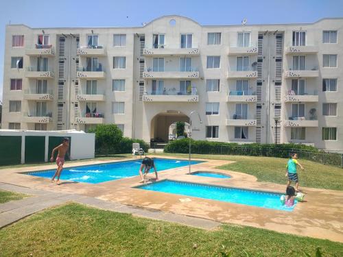 a group of people playing in a swimming pool with a dog at Departamento Amoblado a Pasos del Faro in La Serena