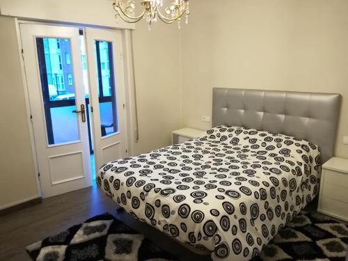 a bedroom with a bed with a black and white comforter at Las Higueras -casa con jardín- in Pomaluengo