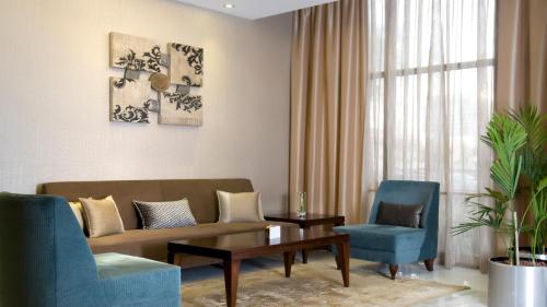 a living room with a couch and two chairs at Copthorne Downtown by Millennium in Abu Dhabi