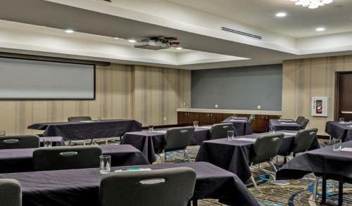 a conference room with tables and chairs and a screen at Holiday Inn Austin Airport by IHG in Austin