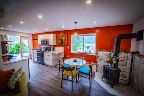 cocina con paredes de color naranja, mesa y fogones en Gallery Suite art-cation vacation!, en Nelson