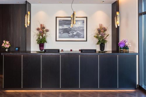 a reception desk in a hotel lobby with flowers at Holiday Inn Berlin City Center East Prenzlauer Berg by IHG in Berlin