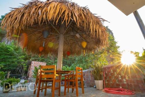 a table and chairs under a straw umbrella at Thien Thanh Hotel in Phong Nha