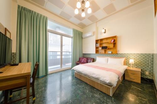 1 dormitorio con cama, escritorio y ordenador en Freedom B&B en Tainan