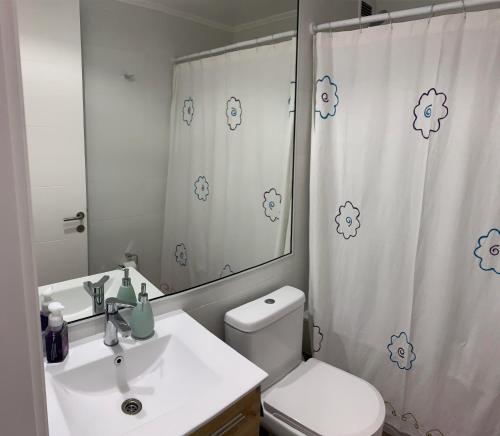 a bathroom with a sink and a toilet and a shower curtain at Departamento Familiar con Terraza Panorámica y a Pasos de la Playa en Punta Puyai in Papudo