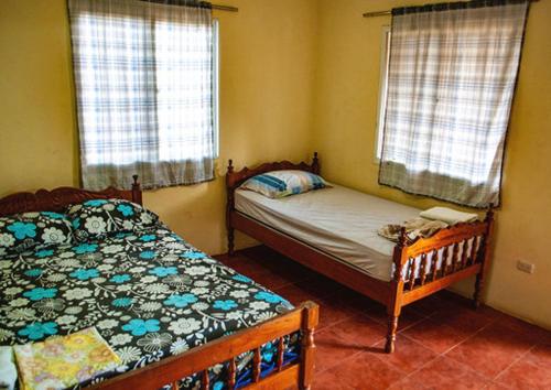 a bedroom with two beds and two windows at Hostal Nathaly in Moyogalpa