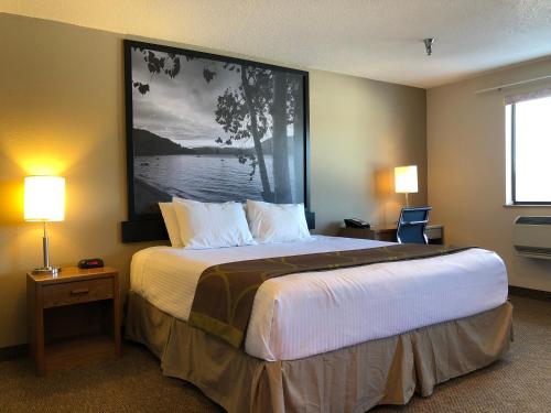 a bedroom with a large bed with a large painting on the wall at Super 8 by Wyndham Salmon Arm in Salmon Arm