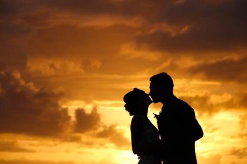 a man and a woman standing in front of a sunset at Wellesley Resort Fiji in Vunaniu
