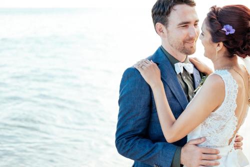 a bride and groom standing next to the water at Wellesley Resort Fiji in Vunaniu