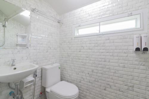 a white bathroom with a toilet and a sink at Rendezvous Oldtown Chiangmai in Chiang Mai