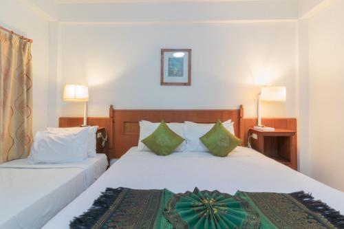 a hotel room with two beds with green pillows at Rendezvous Oldtown Chiangmai in Chiang Mai