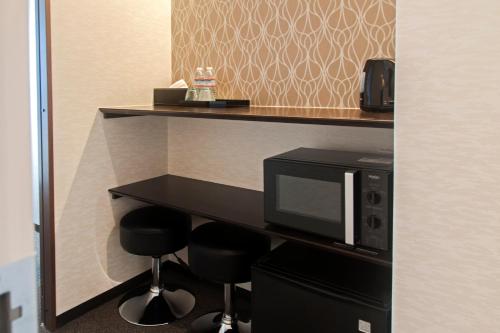 a hotel room with a microwave and two bar stools at UU Inn Kyoto in Kyoto